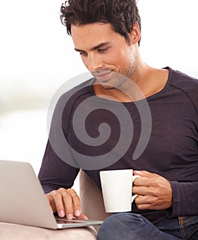 Coffee, laptop and online with man on sofa for social media, networking and connection. Website, streaming and digital