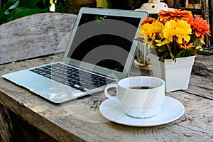 Coffee, laptop on wood floor with flower