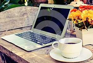 Coffee, laptop on wood floor with flower