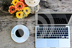 Coffee, laptop on wooden table with flower