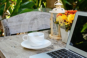 Coffee, laptop on wooden table with flower