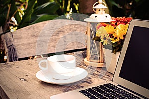 Coffee, laptop on wooden table with flower