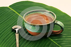 Coffee latte cappuccino in a cup on banana leaf background horizontal