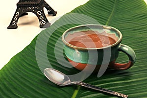 Coffee latte cappuccino in a cup on banana leaf with eiffel tower miniature french background