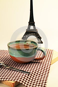 Coffee latte cappuccino in a cup on plaid cloth with eiffel tower miniature french background