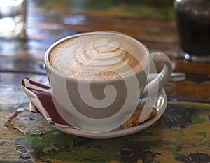 Coffee latte in cup with cream design of heart on top