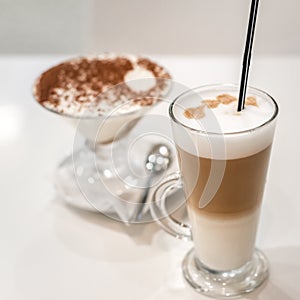 Coffee latte with frothy milk in tall glass, rustic style, white background