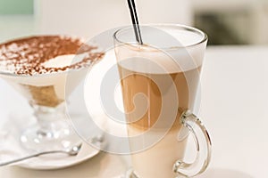 Coffee latte with frothy milk in tall glass, rustic style, white background