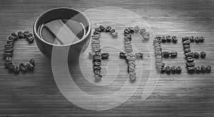 Coffee letters made of beans and cup on vintage boards. Black and white picture