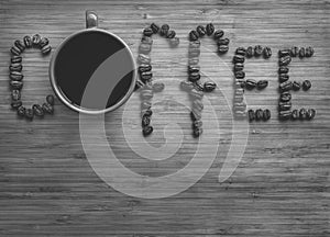 Coffee letters made of beans and cup on vintage boards. Black and white picture