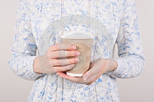 Coffee lover concept. Cropped close up photo of hands holding brown paper cup isolated grey background