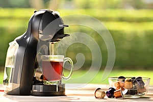 Coffee machine making coffee with capsules on wooden table