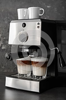 Coffee machine making latte on dark table