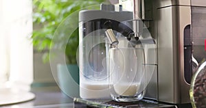Coffee machine preparing and dispensing frothed milk into glass cup