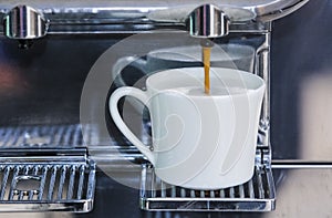 Close-up of espresso pouring from coffee machine to make latte