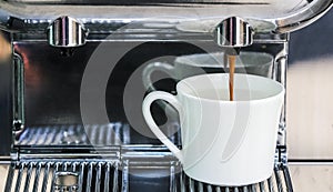 Close-up of espresso pouring from coffee machine to make latte