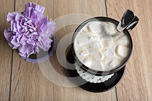 Coffee with marshmallows in a black mug and flower