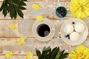 Coffee and marshmallows on wooden background composition with flowers.