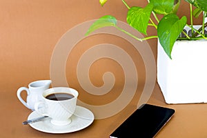 Coffee with milk jug on a brown background.