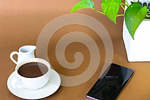 Coffee with milk jug on a brown background.