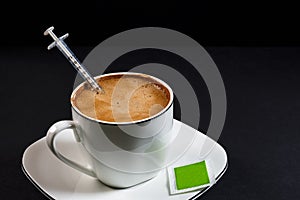 Coffee with milk on a plate with a syringe inside the coffee