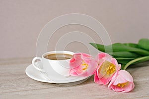 Coffee with milk in a white porcelain cup and saucer, a bouquet of spring pink tulips. Mother`s Day, Valentine`s Day, Easter. Th