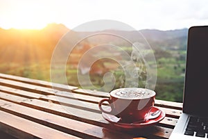 Coffee morning and laptop on wooden table with beautiful mountain background. Worklife balance concept