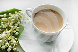 Coffee mug with a bouquet of flowers lily of the valley. View from above, the concept of morning