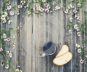 Coffee mug with bread on weathered wooden background with field