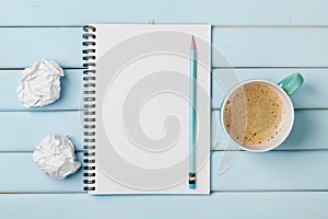 Coffee mug, clean notebook, pencil and crumpled paper on blue rustic table from above, creative research and design ideas concept