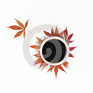 Coffee mug with fall autumn leaves on white background. Flat lay, top view.