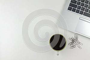 A coffee mug, a laptop, paperclips over the top on a white background