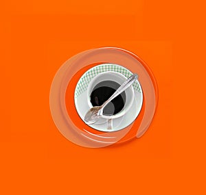 Coffee mug with saucer on orange background