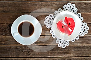 Coffee mug, saucer with red heartshaped gingerbread on the old wooden background. top view
