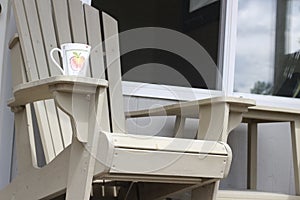 A coffee mug sitting on a Muskoka chair on a dock. Lake and cottages in the background - horizontal orientation. Perfect for