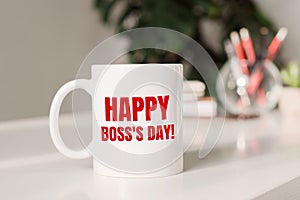Coffee mug with text HAPPY BOSS`S DAY in workplace background
