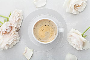 Coffee mug and vintage rose flowers for good morning on gray stone table from above in flat lay style. Beautiful breakfast.