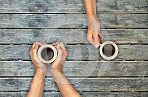 Coffee mugs hands holding on wood table