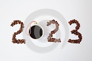 Coffee New Year 2023 concept. Number made of coffee beans. A cup of black espresso coffee as a Christmas ball. On white