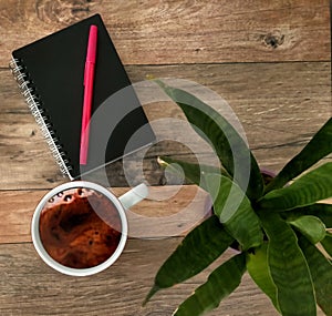Coffee, notebook, pen and plamt