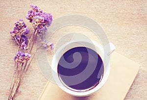 Coffee on notebook with statice flowers, retro filter effe