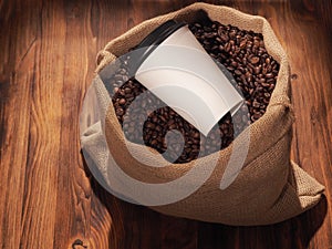 Coffee paper cup in sackcloth bag on wood background