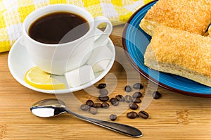 Coffee, pieces of lemon and sugar, plate with flaky biscuits