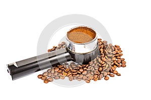 Coffee portafilter filled with finely grounded coffee, and with coffee beans scattered around photo