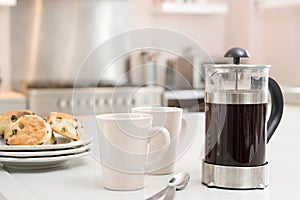 Coffee pot on kitchen counter with scones photo