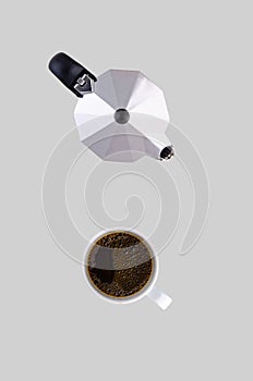 Coffee pot and white cup on a saucer on a gray background.