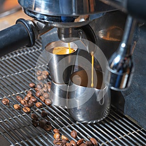 Coffee poured into steel pitcher from machine in cafe