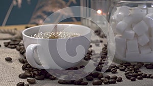 coffee is poured into a white cup, coffee beans, a container with refined sugar