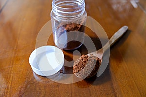 Coffee powder in a jar and on a wooden spoon, on the table