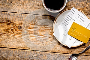 Coffee and receipt bill for payment by credit card on wooden table background top view mockup